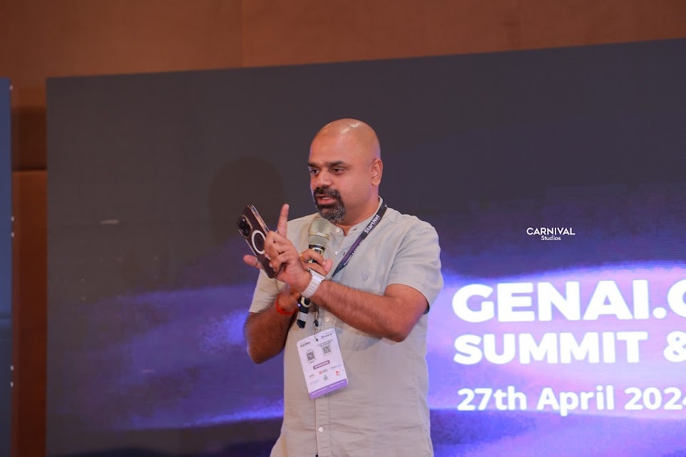 Maran presenting at the GenAI Connect Summit, phone in hand